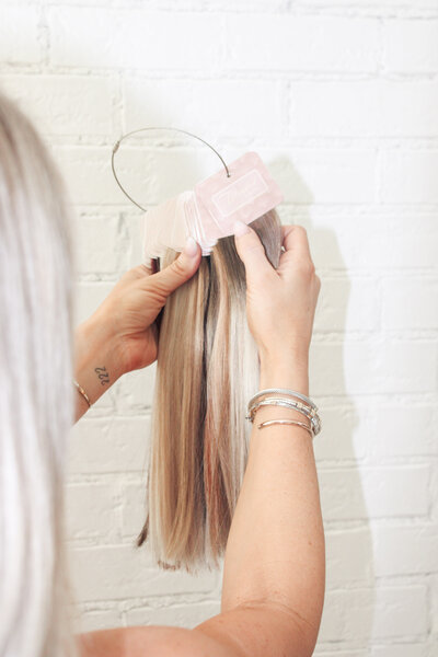 Hand holding a bundle of blonde Blended by Brittni hair extension wefts